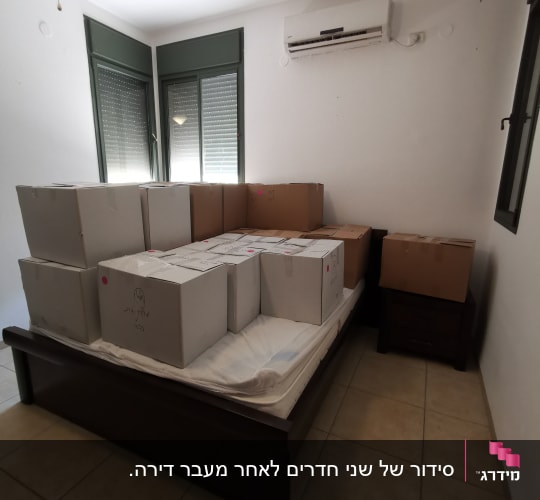 קופסאות קרטון מסודרות על מיטה בחדר ריק